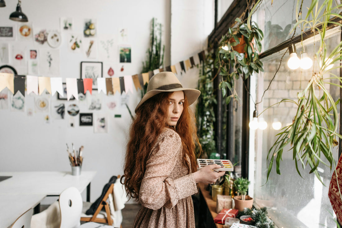 Flowy boho maxi dress with floral print, boho hat in a room with natural boho decor